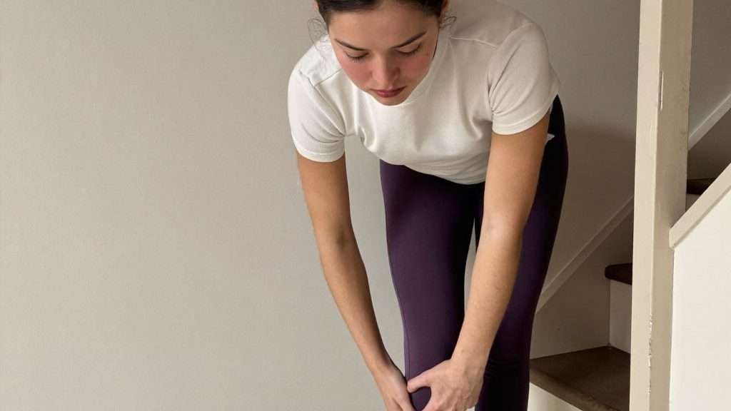 Frau hält schmerzendes Knie auf der Treppe